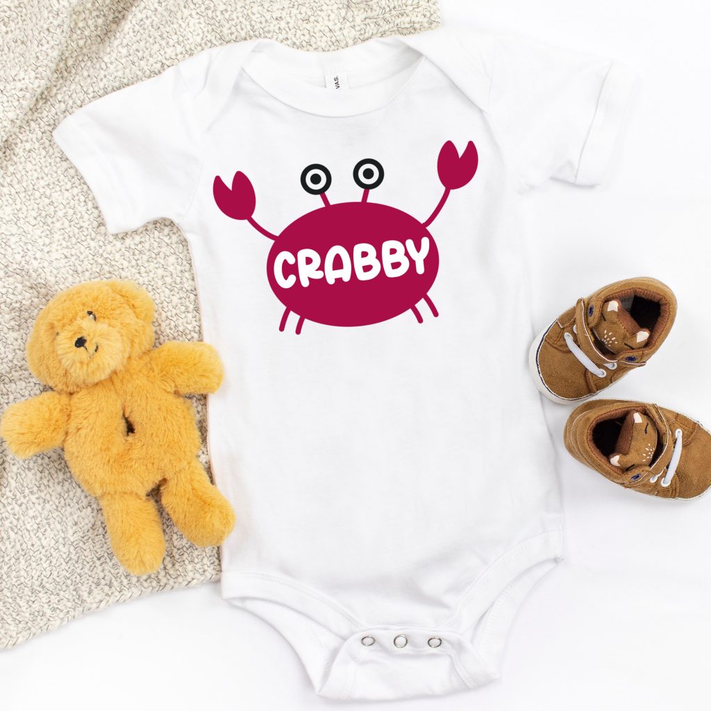 White onesie with a hand drawn crab that says "Crabby" on his shell. 